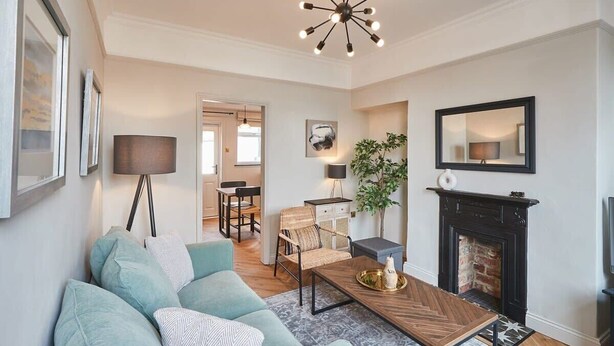A living room with a sofa, coffee table, fireplace, and a dining area in the background. - Host & Stay | The Railman's House (York)