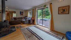 Un salon chaleureux avec une cheminée, un canapé, une table basse et une grande fenêtre avec des rideaux.