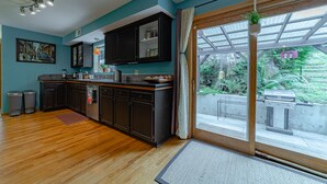 Une cuisine moderne avec des meubles de couleur sombre, un plan de travail en bois et une grande fenêtre donnant sur un jardin.