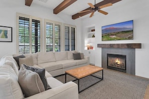 A living room with a sofa, coffee table, fireplace, and a painting on the wall. - Mountain-view 3BR condo in Legacy Villas with pool, fireplace, and balcony. (La Quinta)