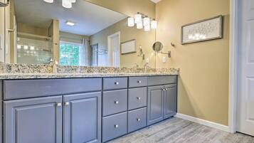 A modern bathroom with a large mirror, granite countertop, and built-in gray cabinets.
