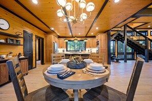 A modern kitchen with wooden cabinets, a central island, and a chandelier.