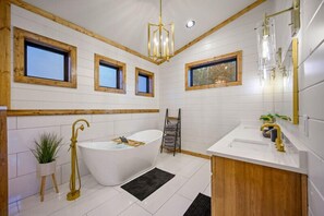 A modern bathroom with a freestanding bathtub, wooden accents, and a large mirror.