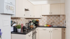 A modern kitchen with white cabinets, a black countertop, and a tiled backsplash.