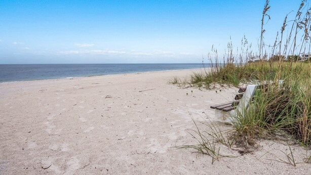 A sandy beach with a clear sky and ocean in the background. - Waters Edge 104s 2 Bedroom Condo by RedAwning (Holmes Beach)
