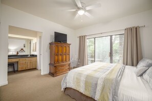 A bedroom with a bed, a wooden cabinet, a television, and a balcony with curtains.