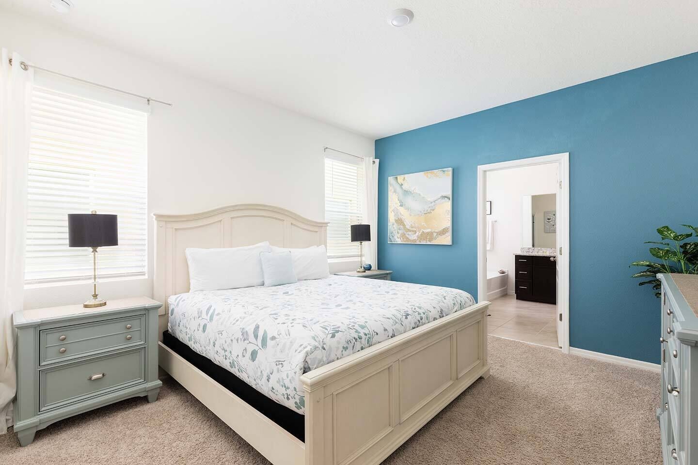 A bedroom with a bed, nightstands, a dresser, and a blue accent wall.