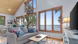 Ein gemütliches Wohnzimmer mit grauem Sofa, einem Couchtisch und Blick auf das Wasser.