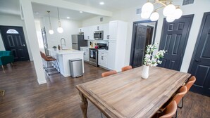 A modern kitchen with white cabinets, stainless steel appliances, and a wooden dining table with chairs.