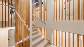 Un escalier moderne avec des rampes et une main courante en bois, menant à l’étage supérieur.