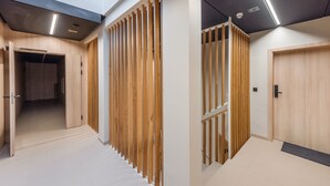 Un couloir moderne avec un lambris en bois, une porte dotée d’une poignée et un luminaire au plafond.