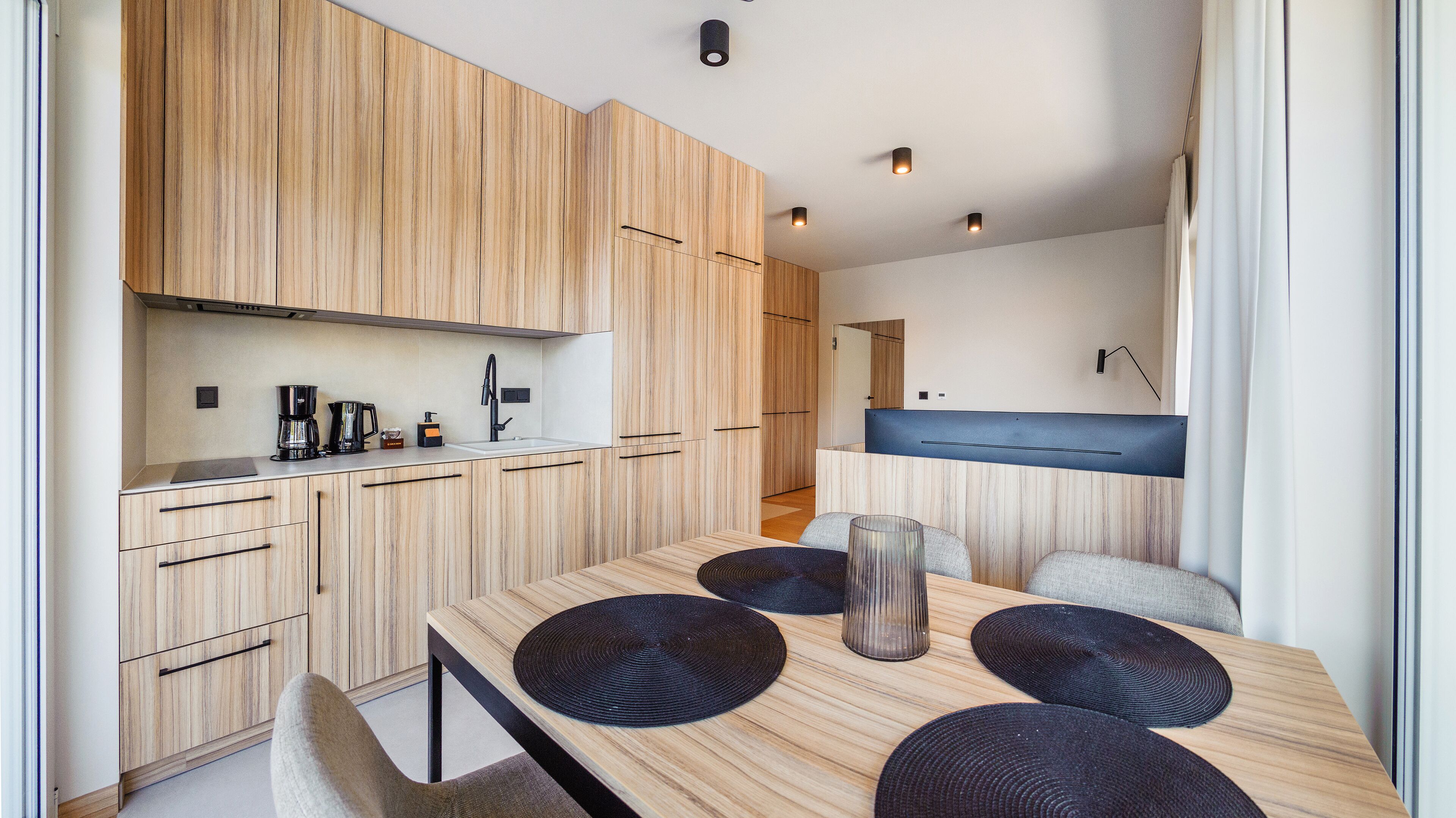 Una cocina moderna con armarios de madera, horno integrado y comedor con mesa y sillas.