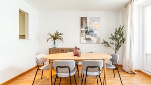 Un comedor con una mesa redonda, seis sillas y dos plantas en macetas.