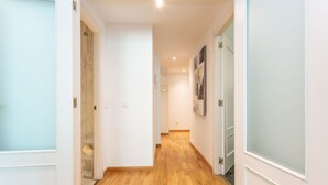 Un pasillo con suelo de madera, paredes blancas y puertas con paneles de vidrio esmerilado.