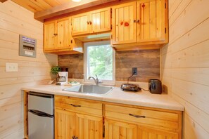 A kitchen with wooden cabinets, a stainless steel sink, a toaster, and a refrigerator.