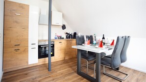Una cocina moderna con armarios de madera, una mesa de comedor con sillas y un colgador para ollas.