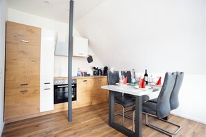Eine moderne Küche mit Holzausstattung, einem Esstisch mit Stühlen und einer hängenden Küchenablage.