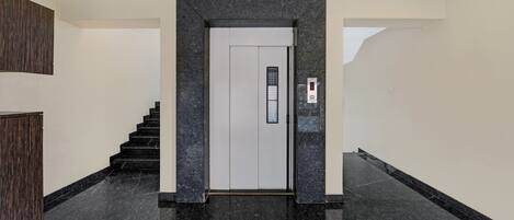 A modern interior with a marble floor, a staircase, and a door with a digital display.