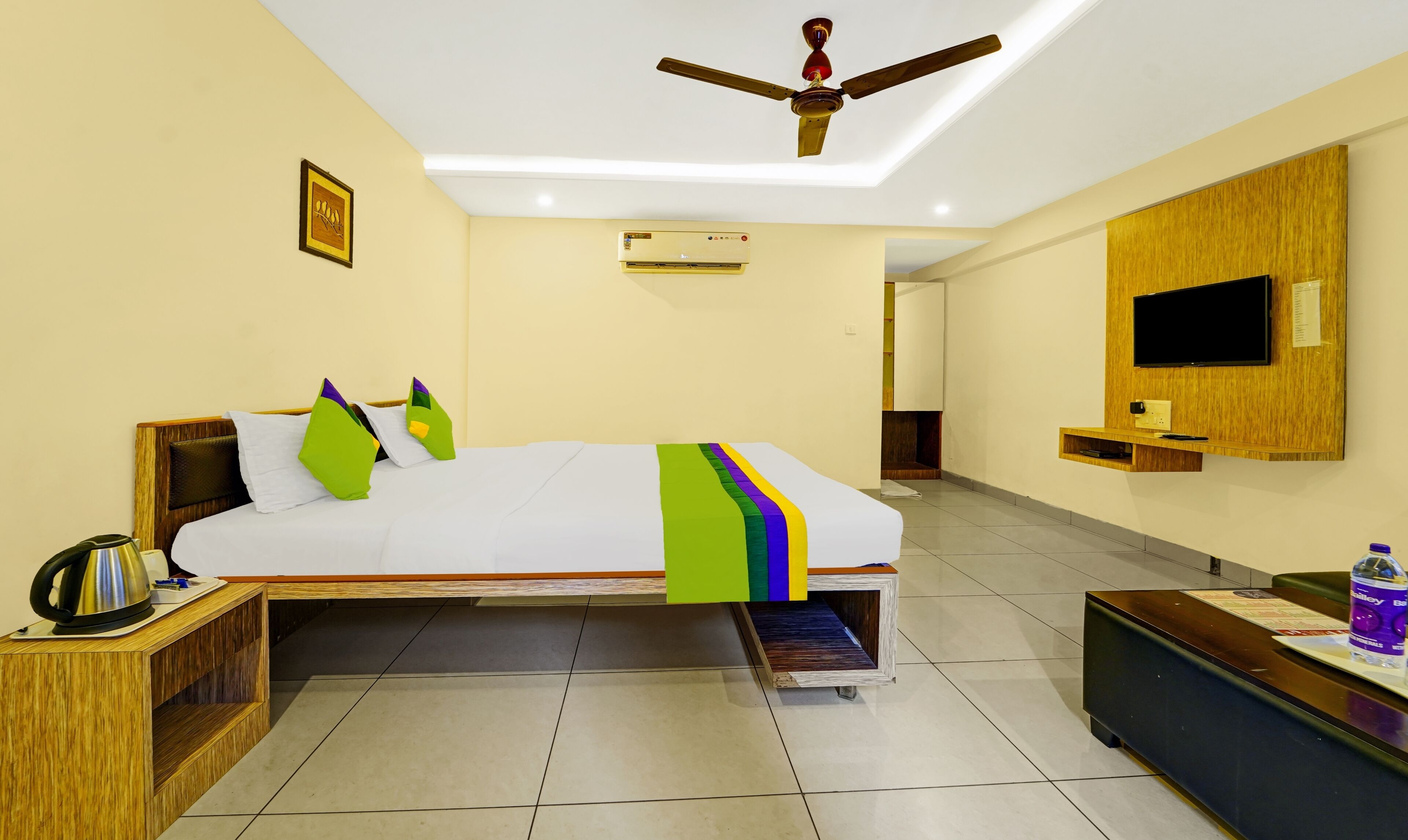 A hotel room with a bed, a desk, a television, and a ceiling fan.