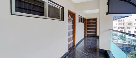 A corridor with a marble floor, a balcony with a glass railing, and doors numbered 403 and 405.