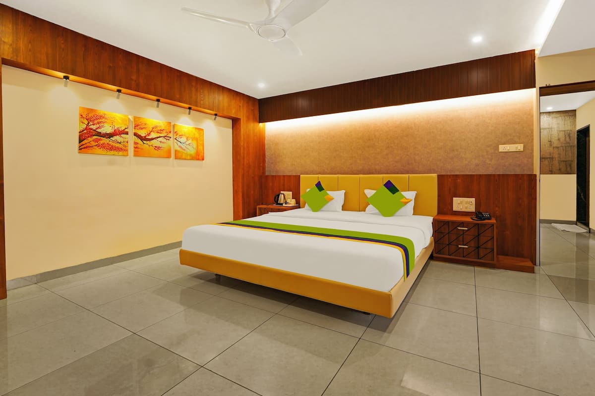 A hotel room with a large bed, wooden paneling on the walls, a ceiling fan, and artwork on the wall.