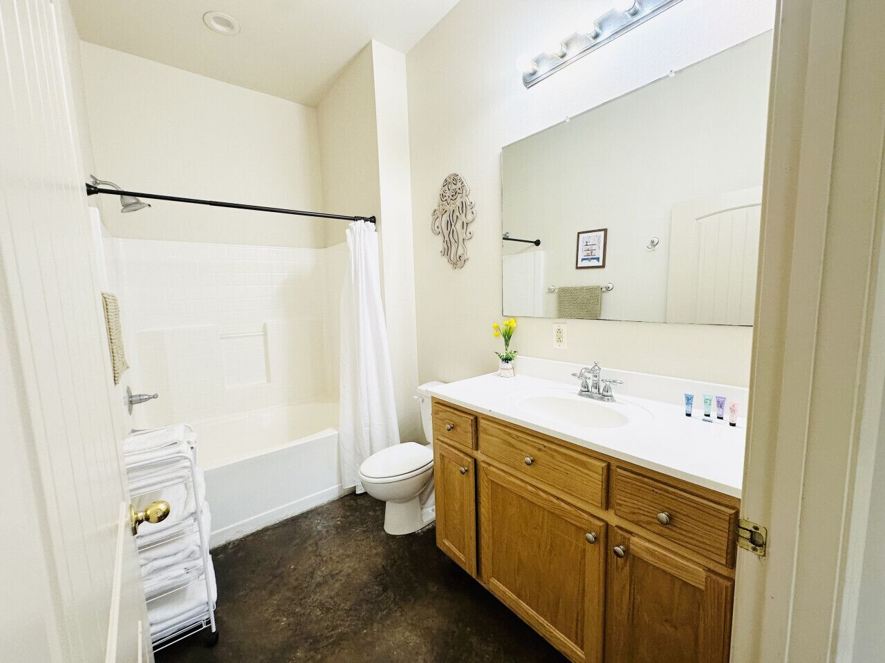 Een badkamer met een bad, toilet en een houten wastafel met een wastafel en spiegel.