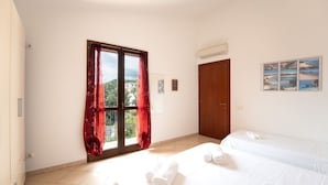 Une chambre d’hôtel avec un lit, une fenêtre avec des rideaux, une porte et un climatiseur fixé au mur.
