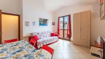 Ein Schlafzimmer mit Bett, Sofa, Kleiderschrank und Schreibtisch mit Fernseher und Fernbedienung.