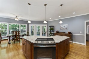 A modern kitchen with a central island, pendant lighting, and a view of the outdoors. - Misty Lake Lodge, home on private lake (Westminster)