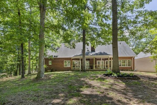 A brick house with a covered porch and large windows, surrounded by trees. - Misty Lake Lodge, home on private lake (Westminster)