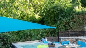 A patio area with a stone floor, a blue umbrella, a hot tub, and outdoor seating with cushions. - Dandy Villas Tsagkarada | Blue Pansy | Mini Pool (Tsagkarada)