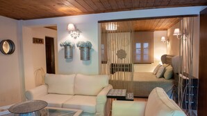 A cozy living room with a sofa, a glass coffee table, and a bed with a canopy. There are decorative wall sconces and a mirror. - Dandy Villas Tsagkarada | Blue Pansy | Mini Pool (Tsagkarada)