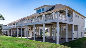 A two-story beachfront house with a covered patio and multiple balconies.