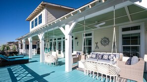 A covered outdoor deck with seating areas, including a swing set and cushioned seating.