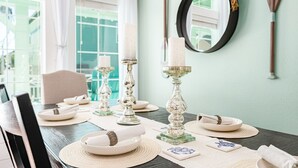A dining table set with plates, napkins, and candles, with a mirror and decorative items on the wall.