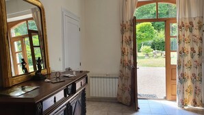 Habitació amb un mirall gran, un taulell de fusta, un radiador i vista a un jardí a través d'una porta.