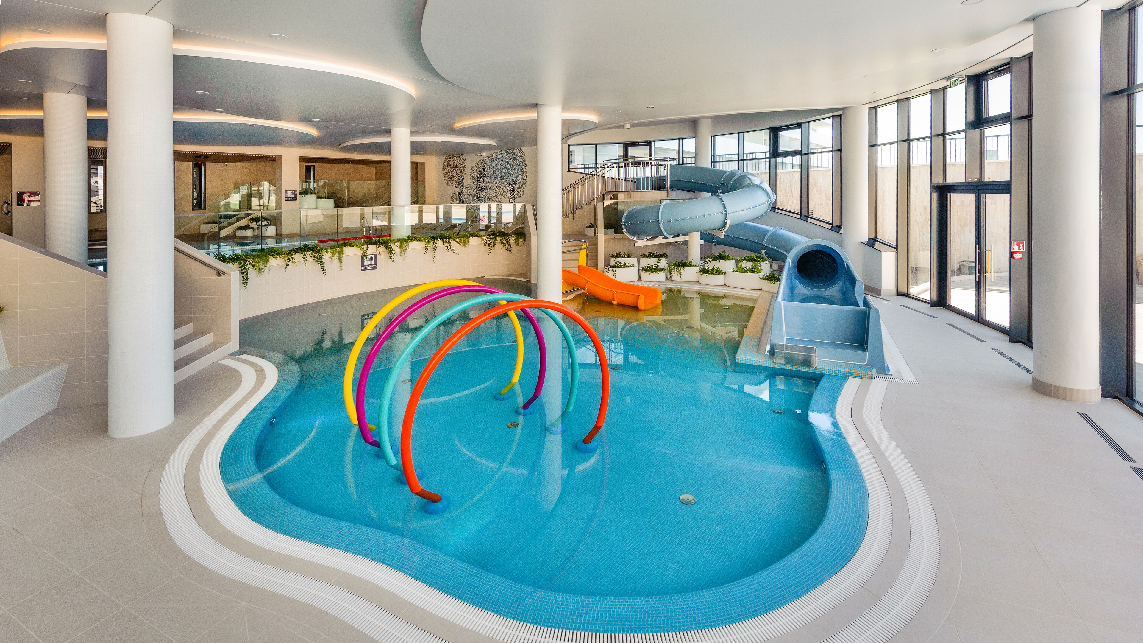 An indoor swimming pool with a water slide and colorful rings.