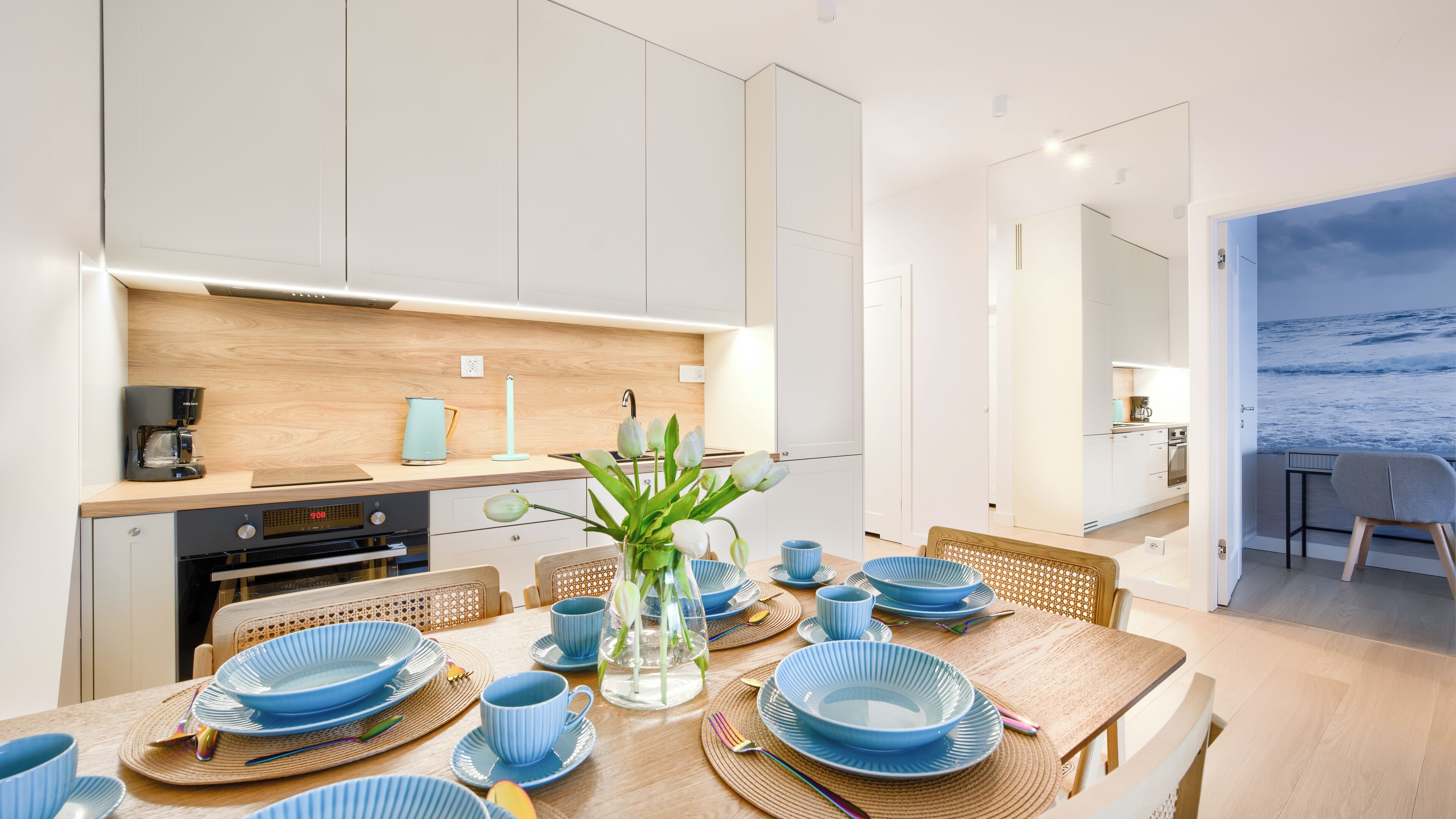 A modern kitchen with white cabinets, a wooden countertop, and a coffee machine.
