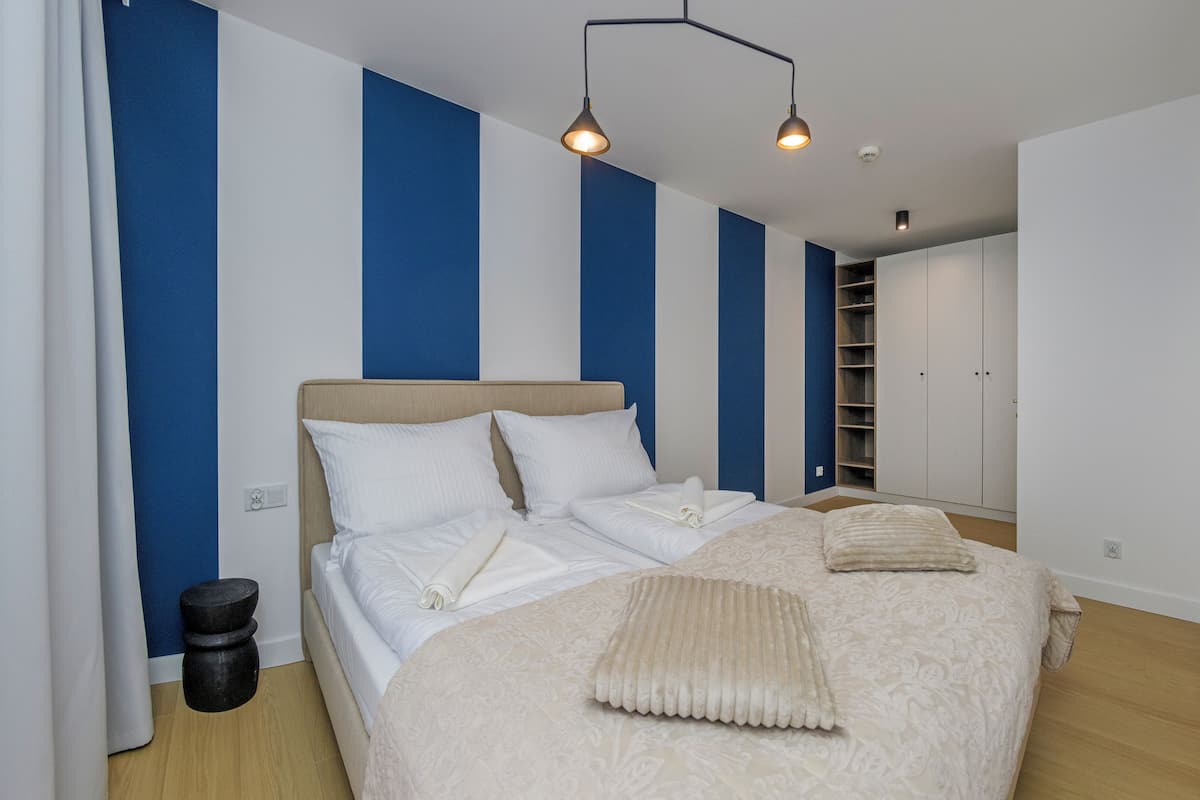 Un dormitorio moderno con cama, mesitas de noche, un armario y televisión.