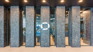 A modern building entrance with a life preserver hanging on a glass door. - Apartamenty Sun & Snow Polanki Aqua (Kolobrzeg)