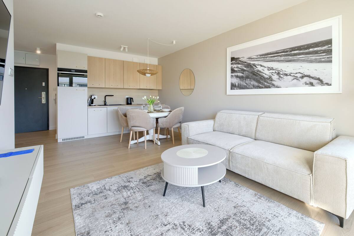 Una sala de estar moderna con sofá, una mesa de centro y un comedor con sillas y una mesa.