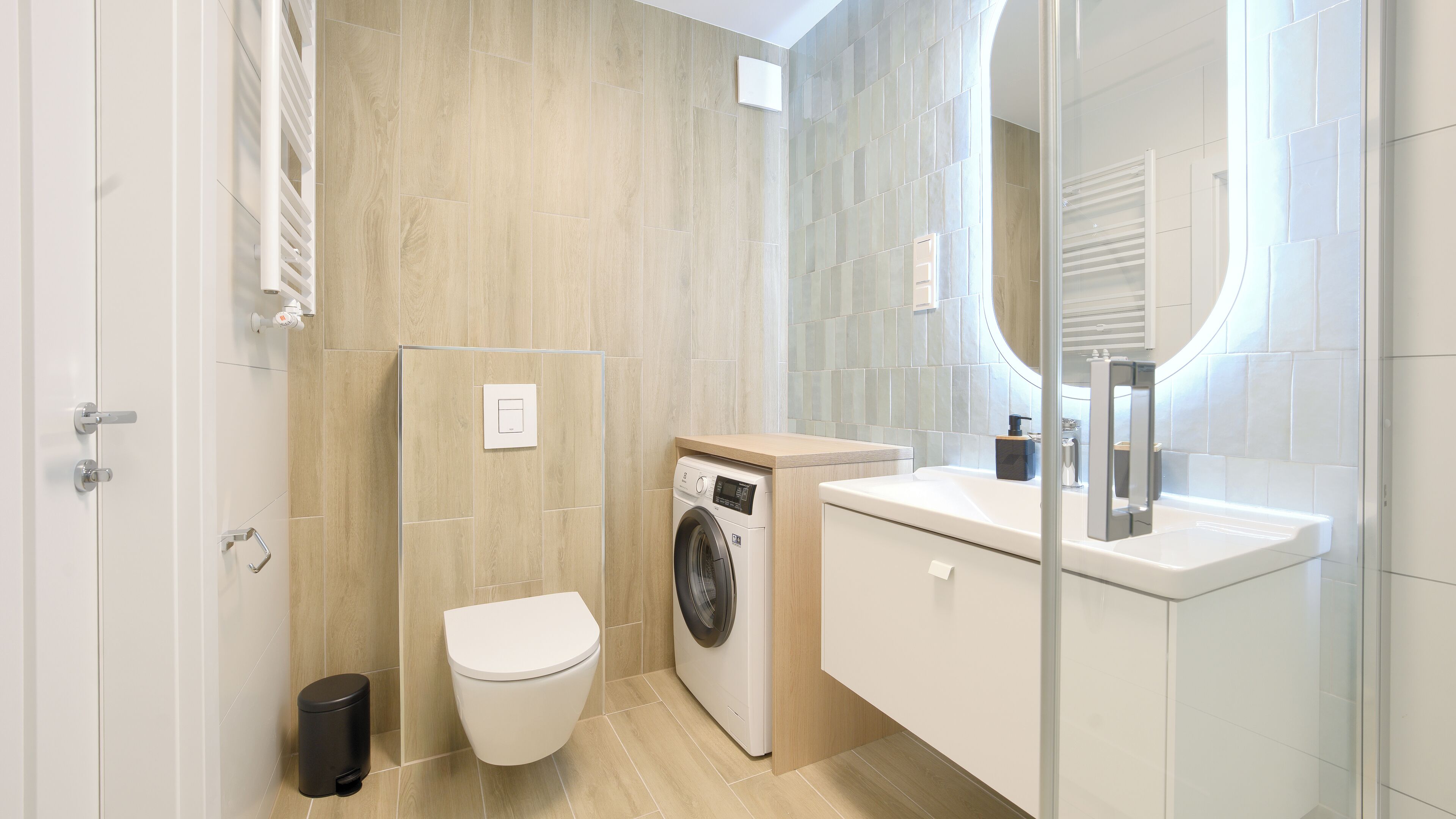 Ein modernes Badezimmer mit Waschmaschine, Toilette und Waschbecken.
