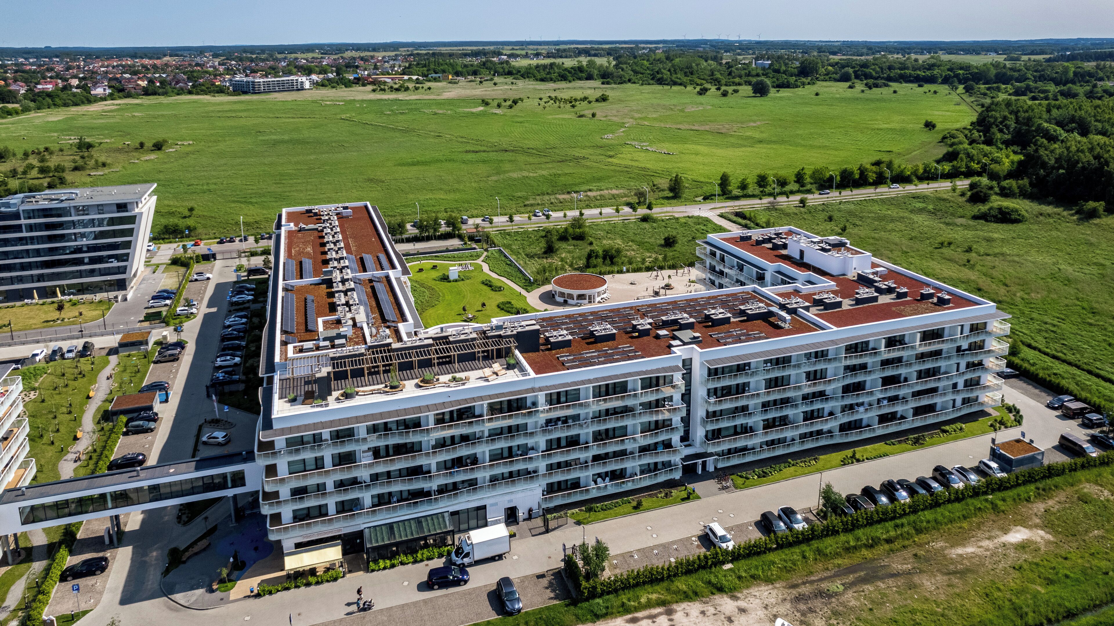 A modern hotel with multiple floors, a rooftop garden, and a parking area.