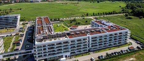 A modern hotel with multiple floors, a rooftop garden, and a parking area.