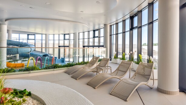 A modern indoor area with large windows, a curved ceiling, and several lounge chairs. - Apartamenty Sun & Snow Polanki Aqua (Kolobrzeg)