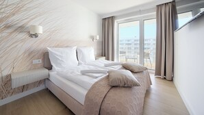 A modern hotel room with a large bed, a bedside table, a lamp, and a view of the balcony. - Apartamenty Sun & Snow Polanki Aqua (Kolobrzeg)