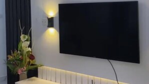 A modern room with a flat-screen TV mounted on a wall with vertical paneling. - Immaculate 2-bed Apartment in Lekki Ajah (Lekki)