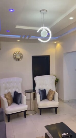 A modern living room with two white armchairs, a small round table, and a black coffee table. - Immaculate 2-bed Apartment in Lekki Ajah (Lekki)