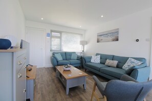 A modern living room with a sofa, a coffee table, and a lamp. - 65 Channel View (Ilfracombe)
