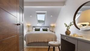 Ein Schlafzimmer mit Bett, Nachttisch, Lampe, Spiegel und Fenster.